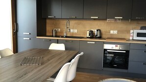 Une cuisine moderne avec des meubles de couleur sombre, un plan de travail en bois et un four encastré.