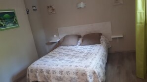 Une chambre à coucher comprenant un lit, une table de chevet et un luminaire fixé au mur.