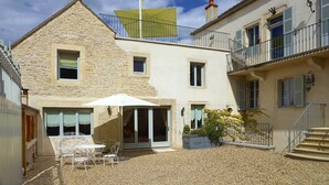 A courtyard with a table and chairs, a covered patio, and a building with a stone facade and balconies. - Chez Hall, La Grange, 2bdr/2bth converted barn bursting with charm, Meursault (Meursault)