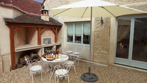 A patio with a round table and white chairs, a white umbrella, and a stone wall. - Chez Hall, La Grange, 2bdr/2bth converted barn bursting with charm, Meursault (Meursault)