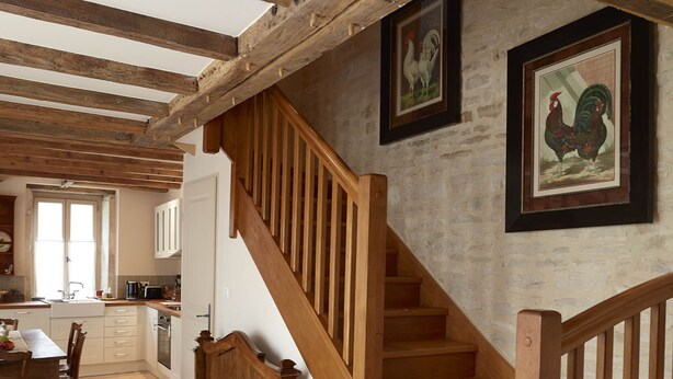 A rustic interior with exposed wooden beams, a wooden staircase, a bench, and a kitchen area. - Chez Hall, La Grange, 2bdr/2bth converted barn bursting with charm, Meursault (Meursault)