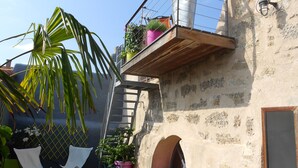 Eine Dachterrasse mit einer Holztreppe, Blumentöpfen und Sitzgelegenheiten im Freien.
