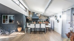 Eine moderne Küche mit einer zentralen Kochinsel, einem Essbereich mit Stühlen und einem großen Fenster.