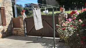 Een stenen gebouw met een houten poort, een droogdoek en potplanten met bloemen.