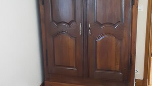 Een grote houten garderobe met twee deuren in een kamer met houten vloer.