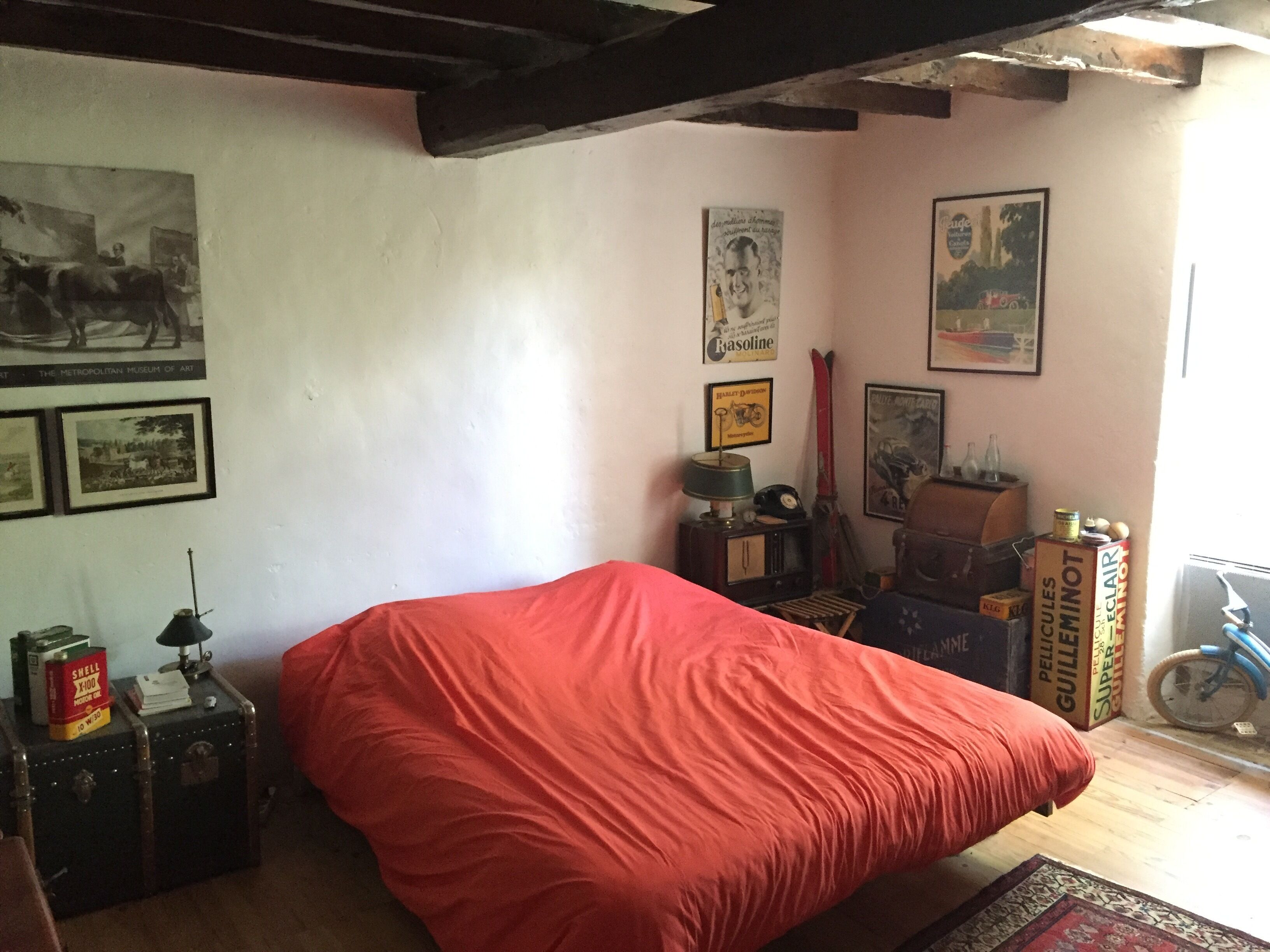 A room with a bed, vintage posters, a motorcycle, and a bicycle.
