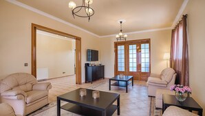 Una sala de estar con sofá, sillón, mesa de centro y televisor sobre un mueble.