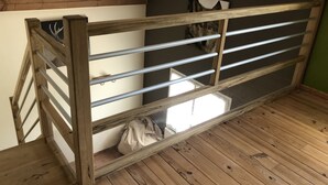 A wooden bunk bed with metal railings, a window, and a bag on the floor.