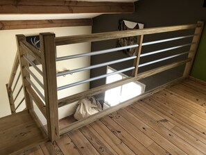 A wooden bunk bed with metal railings, a window, and a bag on the floor.