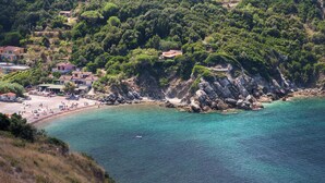 A coastal area with a beach, rocky cliffs, and buildings.