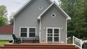 A two-story house with a front porch, a covered deck, and a garage. - Beautiful Cabin on Beach Resort in Northern Michigan! (Bellaire)