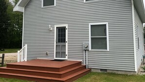 A two-story house with a front porch, a door, and two windows. - Beautiful Cabin on Beach Resort in Northern Michigan! (Bellaire)