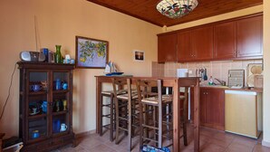 Una cocina con armarios de madera, una mesa de comedor con sillas, un aparador con puertas de cristal y una lámpara colgante.