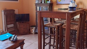Comedor con mesa y sillas de madera, televisor y un mueble con botellas.