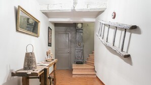 Un couloir étroit avec une table en bois, une horloge et un escalier menant à une autre pièce.