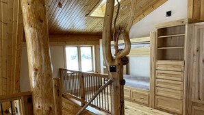 Interior de madera con ventilador de techo, una escalera y una cama con colchón texturizado.