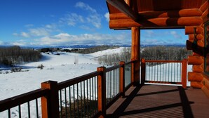 Una terraza de madera con vistas a un paisaje nevado y montañas.
