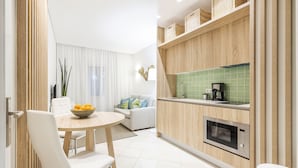 Una cocina moderna con armarios de madera, microondas integrado y comedor con mesa redonda y sillas blancas.