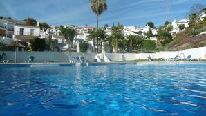 Ein Swimmingpool mit Liegestühlen und Blick auf weiße Gebäude mit roten Ziegeldächern.