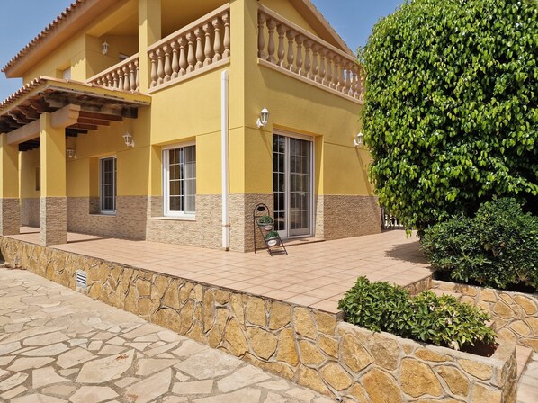 A building with a balcony, stone wall, and a well-maintained garden.