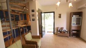 Un amplio espacio de sala con una escalera, un sofá, un televisor y una zona de cocina.