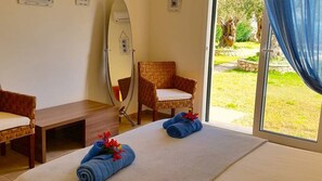 Una habitación con cama, una silla, un espejo y vistas al exterior.