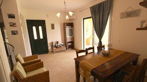 Un comedor con una mesa y sillas de madera, un sofá, un armario y una puerta.
