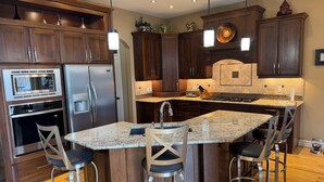 Eine moderne Küche mit dunklen Holzschränken, Edelstahlgeräten, Granit-Arbeitsplatten und Barhocker.