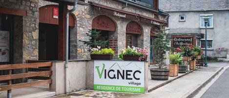 Ein Steinhaus mit einem Schild für den Ort VIGNEC, einem Restaurant und einem Schild für L'Authentique.