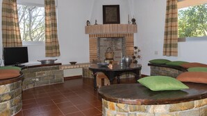 A cozy living room with a stone fireplace, a television, and comfortable seating. - Studio on the sunset beach (Attiki)