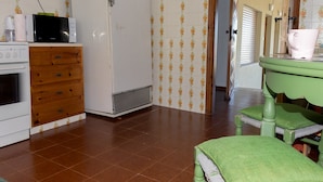 A kitchen with a white refrigerator, a microwave, a wooden cabinet, and a green chair. - Studio on the sunset beach (Attiki)