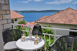 Un balcon avec une table, deux chaises, un vase de fleurs et une lampe.