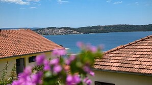 Eine Küstenstadt mit terrakottafarbenen Dächern, blauem Himmel und Blick auf das Meer.