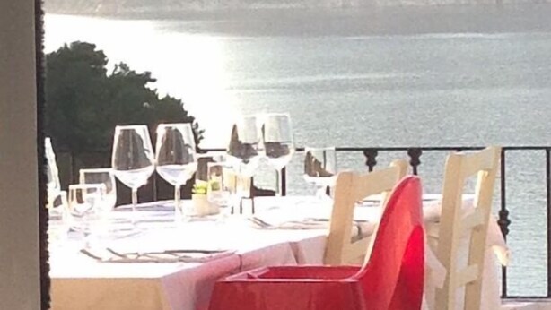 Ein Tisch ist für das Essen gedeckt, mit Blick auf das Meer und einem Berg im Hintergrund.