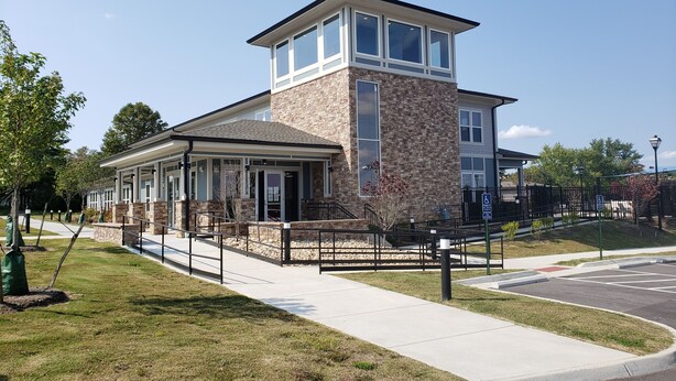 A modern building with a stone facade, large windows, and a covered entrance area.