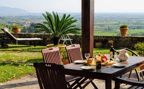 Un espace de restauration en plein air avec une table dressée pour deux personnes, offrant une vue sur un paysage pittoresque.