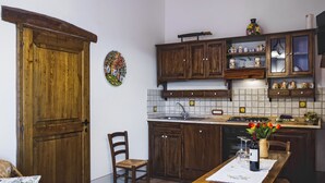 A kitchen with wooden cabinets, a tiled backsplash, and a dining table with a vase of flowers.