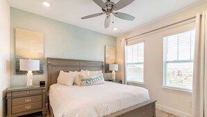 A bedroom with a bed, nightstands, a ceiling fan, and a window with blinds.