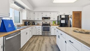Una cocina moderna con armarios blancos, electrodomésticos de acero inoxidable y piso de madera.