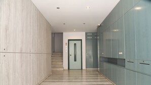 A hallway with a light-colored floor, a green door, and a staircase leading to an elevator. - Economic Studios B9 (Iraklion Crete)