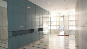 A spacious hallway with teal cabinetry and a tiled floor, leading to a door with a view of parked cars outside. - Economic Studios B9 (Iraklion Crete)