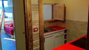 Een compacte keuken met houten details, een rode aanrechtblad en een geïntegreerde vaatwasser.
