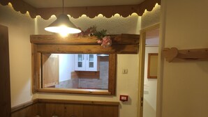 Een eetgedeelte met een houten tafel, stoelen, een hanglamp, een raam met uitzicht en hartvormige uitsneden in de muur.