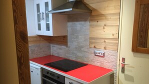 Een kleine keuken met een rood aanrecht, een ingebouwde oven en een witte kast.