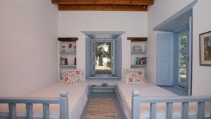 A cozy room with two beds, a window, and a door. - Traditional villa in Hora with sea view to the Aegean  (ΠΑΤΜΟΣ)