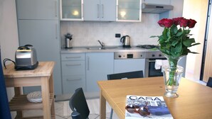 Uma cozinha com uma torradeira, um vaso com flores e uma revista sobre a mesa.