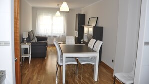 Una sala de estar moderna con comedor, que incluye un sofá, una mesa de centro, una mesa de comedor con sillas e iluminación colgante.