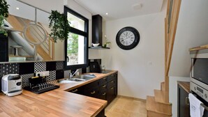 A modern kitchen with a wooden countertop, a built-in oven, and a black clock on the wall.
