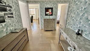 A hallway with patterned wallpaper, wooden furniture, a dresser, and a small table with a phone. - Wonderful sea view - Santa Maria (Menton)