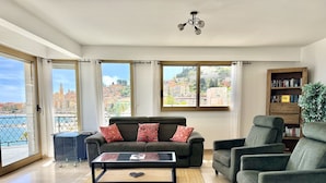 A living room with a sofa, armchair, coffee table, and a bookshelf. - Wonderful sea view - Santa Maria (Menton)